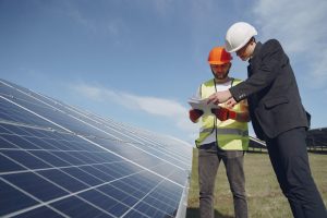 focused men with documents in hardhats at solar energy station